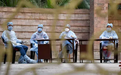 Medics arrive to take blood samples of residents of Spanish Garden residential complex after a COVID-19 positive case was detected in an apartment, in Guwahati. Image by David Talukdar / Shutterstock. India, 2020.